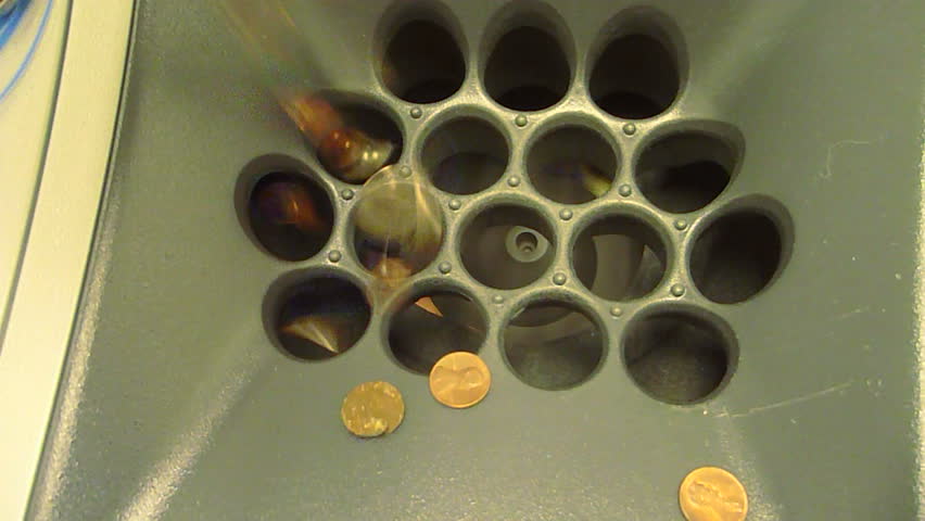 United States coins pouring into change counter at bank add and total up amount.