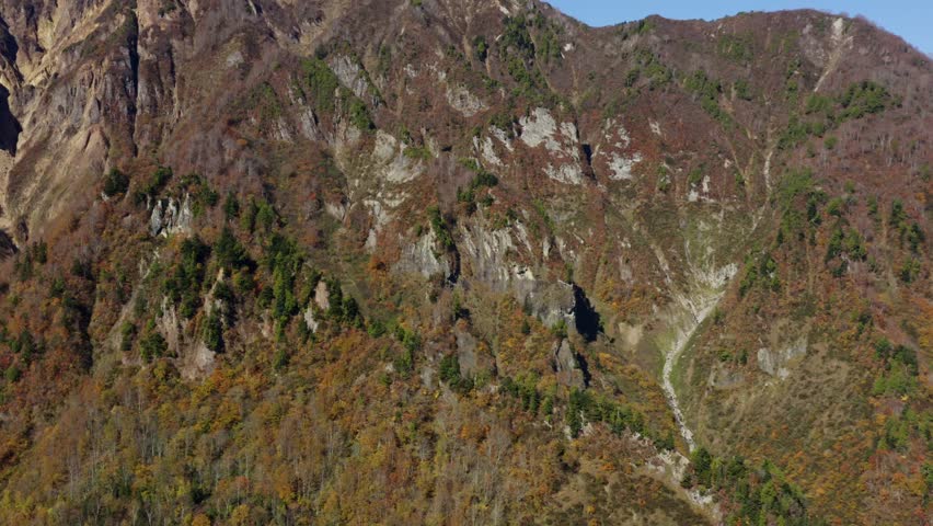 Drone footage: Spectacular mountain rock face surrounded by vivid autumn leaves
