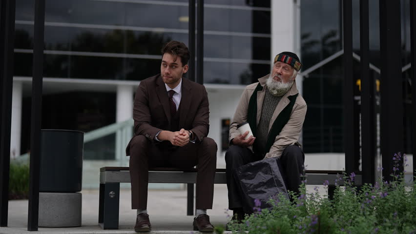 Portrait of talking young businessman and old homeless man sitting on bench, representing growing gap between rich and poor in modern society. Concept of social issues and economic disparity.