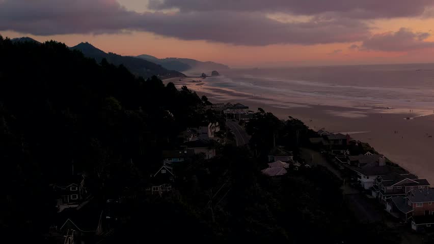 Aerial cinematic drone flight showcasing a beautiful scenic beach with a peaceful atmosphere late in the evening after sunset. Cannon Beach, Oregon.