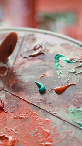 Vertical Video Talented artist using modern tools and painting supplies to create an artwork, mixing watercolors on a palette during his creative process. Man working on a masterpiece. Close up