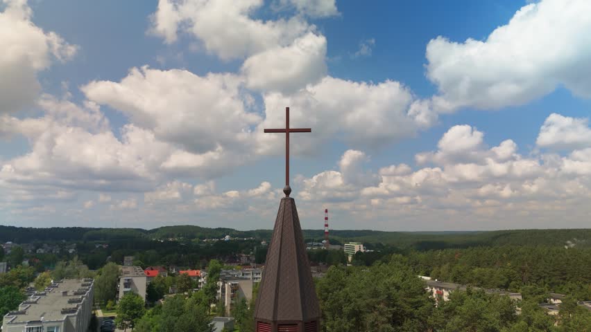 An aerial footage of the cross atop the Grigiskiu Holy Spirit Catholic Church on a sunny day in Grigiskes, Vilniaus, Lithuania