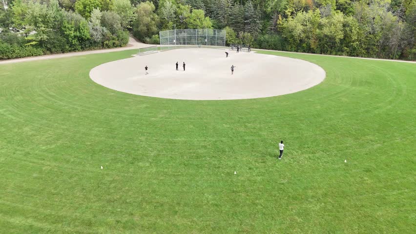 A Drone shot over a green lawn park and boys playing cricket at Kitchener, Ontario, Canada