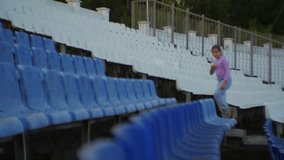 Young girl carefully climbing a section of empty blue bleachers at a sports stadium, showcasing determination and agility in vibrant - Powered by Shutterstock - Get 15% off with code: PIKWIZARD15
