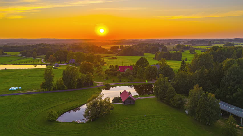 Hyperlapse drone shot of sunset above a rural farm and countryside fields