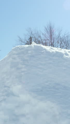 SLOW MOTION: Extreme snowboarder man riding in sunny mountain snow park and jumping over big air kicker in sunny winter. Young pro snowboarder jumping over the sun
