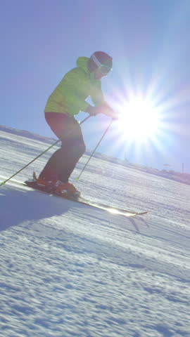 SLOW MOTION FOLLOW Extreme young skier with helmet skiing in perfect early morning cold winter day on a fresh groomed piste at the ski resort. Sun flare is shinning above the fog in the valley