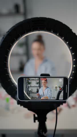 Beauty blogger woman recording makeup tutorial by smartphone in home studio. Professional makeup artist filming review on new cosmetics, advertising brands in blog in social media, record on screen