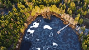 Stunning aerial shot of a partially frozen lake surrounded by lush green forest in a winter setting. The wooden dock extends into the icy waters, adding a rustic charm to this natural work of art. - Powered by Shutterstock - Get 15% off with code: PIKWIZARD15