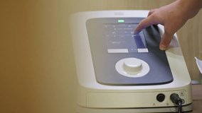 Close-up of a person's hand interacting with a modern medical or therapy device screen, adjusting settings with a touch and rotary knob interface. Concept of medical technology and precision control. - Powered by Shutterstock - Get 15% off with code: PIKWIZARD15