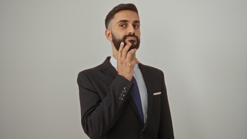 Young hispanic man in a suit with a beard isolated over a white background wall posing confidently - Powered by Shutterstock - Get 15% off with code: PIKWIZARD15