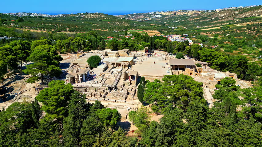 The ancient Knossos Palace ruins in Crete, Greece surrounded by lush trees and rolling hills