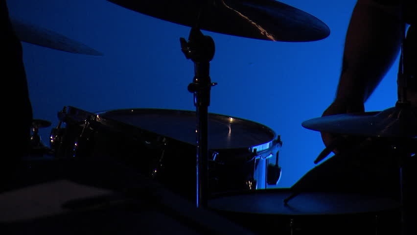 Musician playing a crash cymbal on a drumset with a blue background