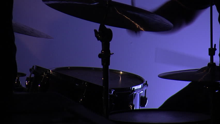 Musician playing a crash cymbal on a drumset with a purple background