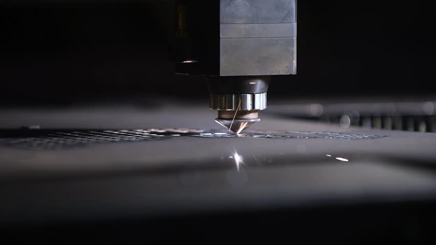 A CNC laser cutting machine precisely cuts through a metal sheet, producing bright sparks. This industrial process showcases modern technology and high-tech metalworking