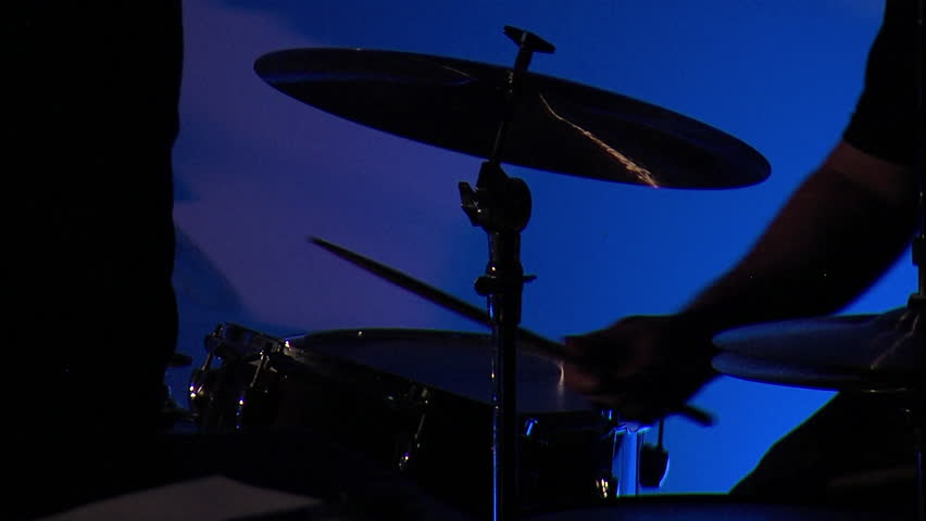 Musician playing a crash cymbal on a drumset with a blue background