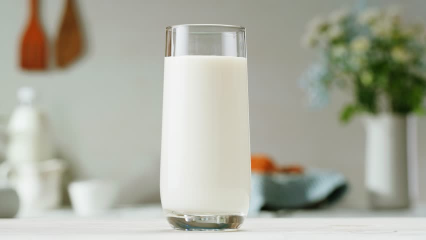 Pouring kefir yogurt into glass cup close-up. Glass with kefir or milk, lactic acid product dairy products concept. Drinking fresh lactose free in morning.