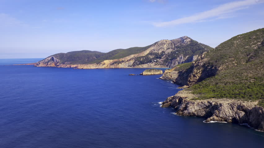 Ibiza Coast Landscape with Bays and Turquoise Water with Clear Blue Skies – Rising Drone Pan Left 