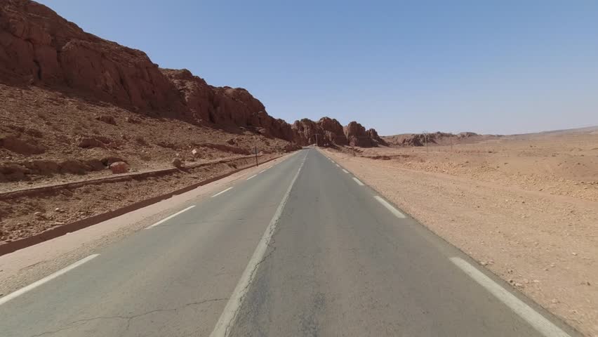 Driver point of view from a motorcycle across the desert, towards Brezina, Algeria. Nice rock formations.