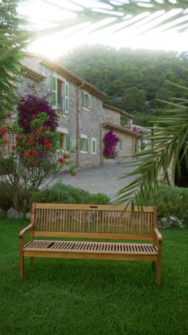 Woman relaxing on a bench in a scenic outdoor garden with lush greenery and colorful flowers, wearing a black dress, mallorca, spain