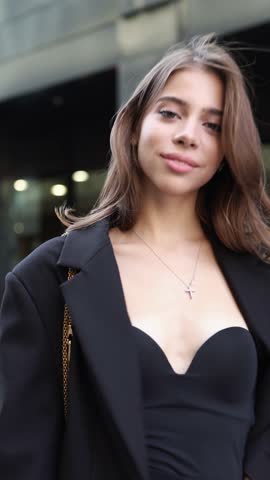 Portrait Stylish young brunette woman with long hair wearing elegant outfit oversize black blazer and top, beautiful model stands, poses at city. Modern high fashion, contemporary street style