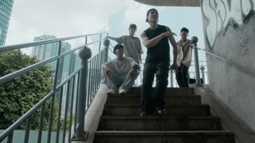 Low angle view of group of young Asian people looking at man practicing hip hop dance moves on staircase outdoors - Powered by Shutterstock - Get 15% off with code: PIKWIZARD15