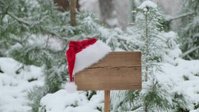 Santa Claus Hat on wooden road sign, nature background with pine trees and snowy forest. Concept of Christmas holiday and happy New Year. Winter nature - Powered by Shutterstock - Get 15% off with code: PIKWIZARD15
