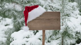 Santa Claus Hat on wooden road sign, nature background with pine trees and snowy forest. Concept of Christmas holiday and happy New Year. Winter nature - Powered by Shutterstock - Get 15% off with code: PIKWIZARD15