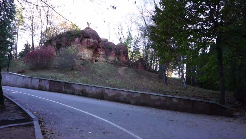 An asphalted path and a stone barrier wall in the park in the small town in the South of Russia in late autumn