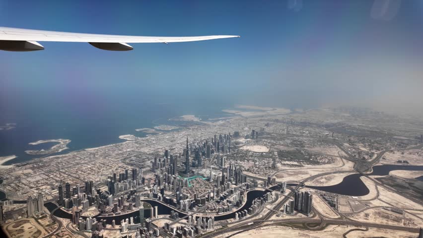 Airplane is flying over dubai, offering a breathtaking view of the city's impressive skyline, characterized by towering skyscrapers and the iconic palm jumeirah