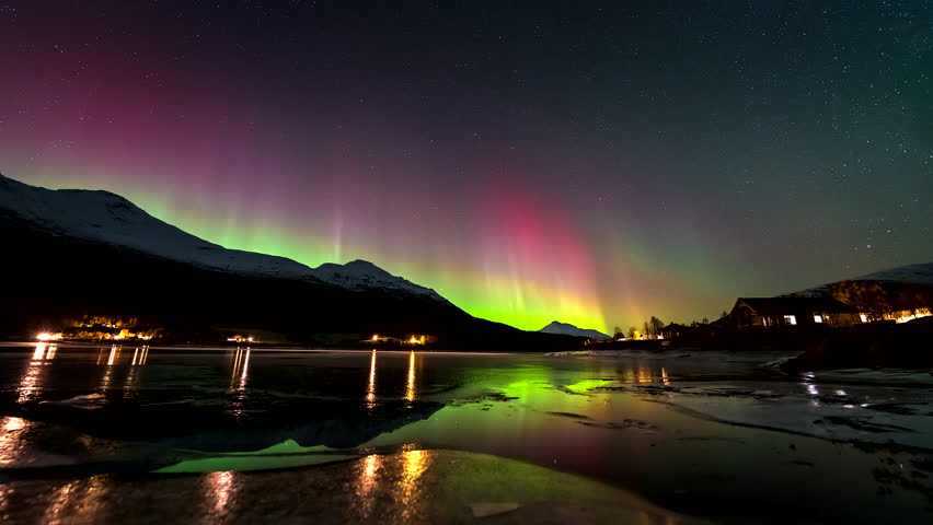 Northern lights dance in night sky over Lakselvbukt with rising tide, timelapse