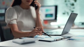 Businesswoman reviewing charts and graphs while engaging in a phone conversation in a professional office setting - Powered by Shutterstock - Get 15% off with code: PIKWIZARD15