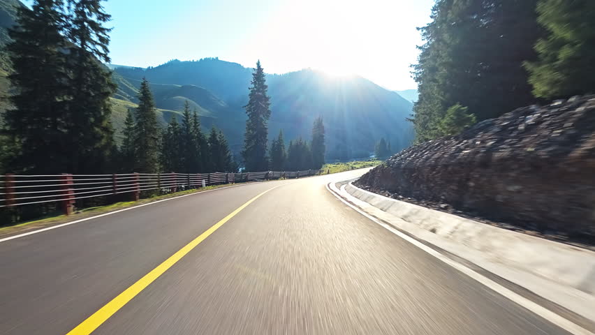 Driving car on a mountain road. Ahead is a green forest and mountain nature landscape in summer.