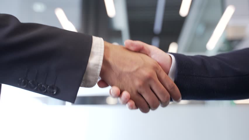 Close up of business handshake symbolizing teamwork and cooperation. Two male professionals shaking hands after sealing a deal in a modern office. Concept of partnership among colleagues. Mutual trust
