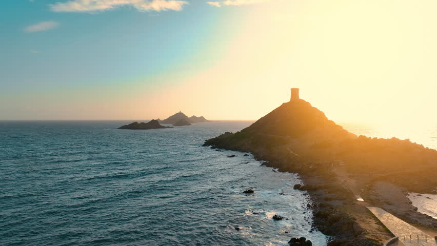 Explore the stunning coastal view of the island with a watchtower at sunset, capturing the beauty of nature and the sea near the shore. Corsica