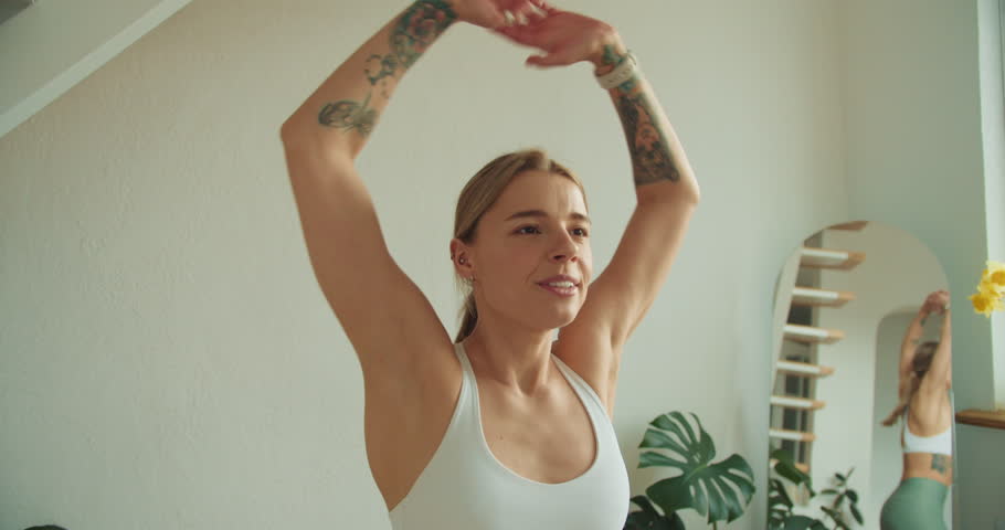 Happy Woman Raising Arms Post-Workout: Embracing Joy and Vitality in a Minimalist Fitness Space with Energized Expressions
