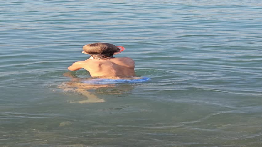 A boy dives into the water on the sea beach
