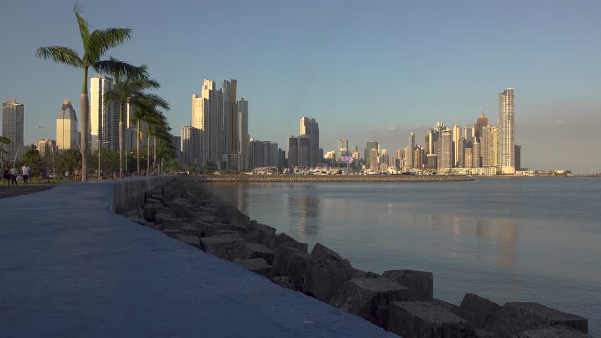 The waterfront in Panama City with skyscrapers, palm trees, and a path for people to walk