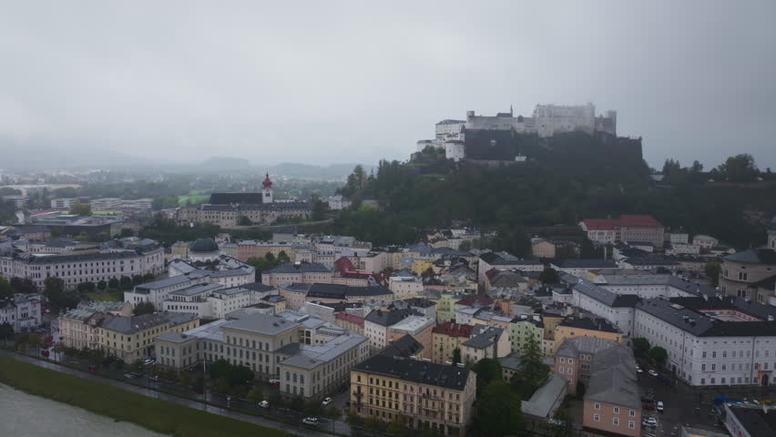 Panning over Salzburg reveals a breathtaking cityscape in Austria, featuring the majestic Hohensalzburg Fortress standing atop a hill