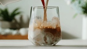 Ice coffee latte with cream being poured into it showing the texture and refreshing look of the drink, with a clean background. - Powered by Shutterstock - Get 15% off with code: PIKWIZARD15
