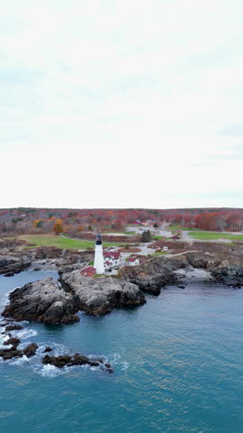 Stunning aerial view of iconic Portland Head Light, beautifully framed by the vibrant and colorful fall foliage, showcasing the remarkable autumn beauty found throughout New England, Portland Maine