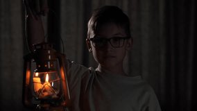 Young boy holding a kerosene lantern in a dark room - Powered by Shutterstock - Get 15% off with code: PIKWIZARD15