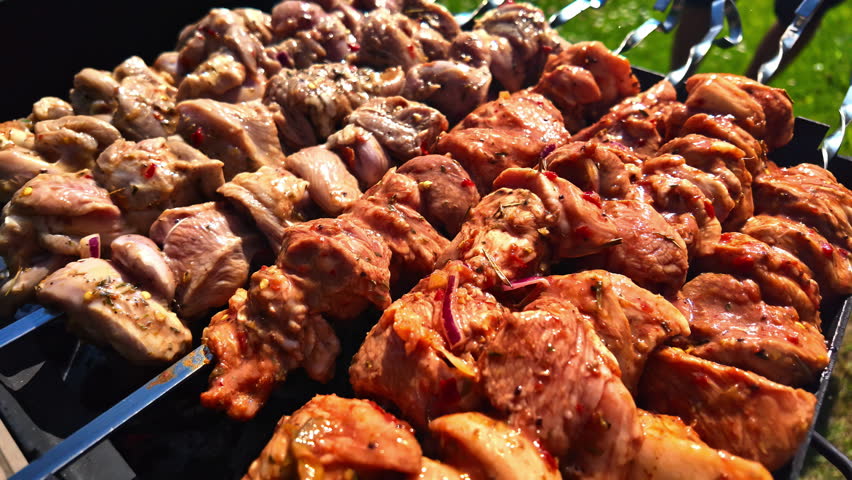 Close-up shot of roasted chicken meat on a skewer in the garden barbecue camping