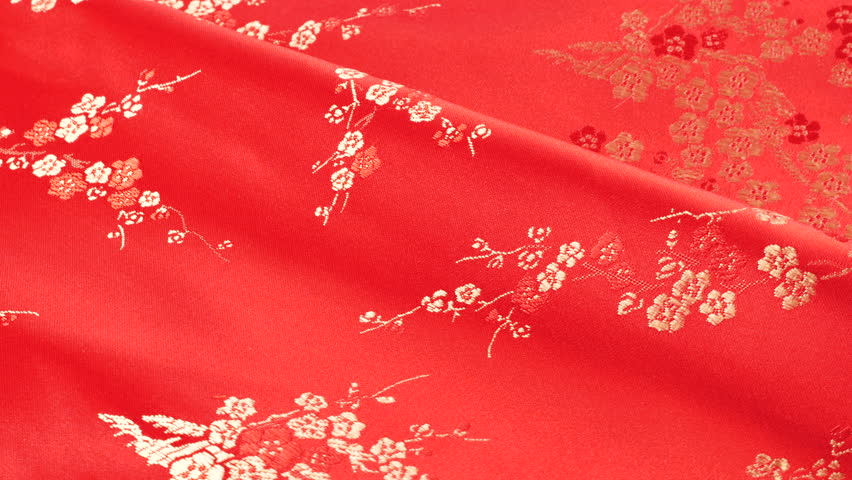 Lustrous red silk textile punch shade fabric background with floral embroidery in oriental style with plum blossom flower pattern. Soft folds of brocade shimmers beautifully on a rotating display.