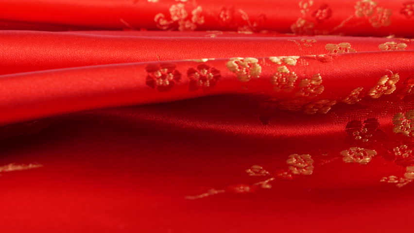Lustrous red silk textile fabric background with floral golden embroidery in oriental style with plum blossom flower pattern. Soft folds of brocade shimmers beautifully on a rotating display case. 