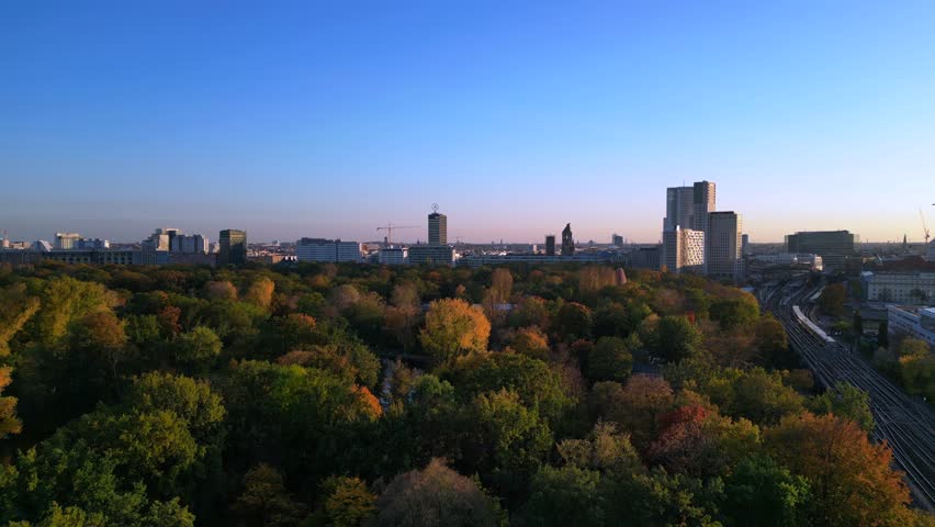 Train in tiergarten park at autumn sunset. Dramatic aerial view flight drone