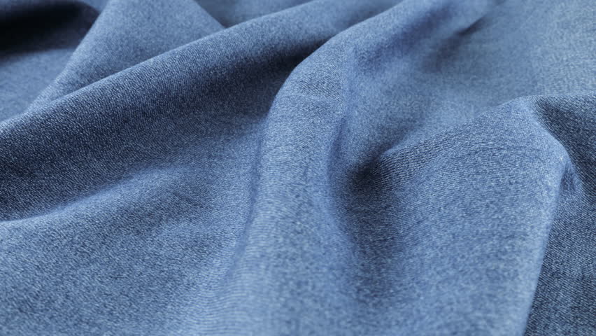 Soft folds of gray-blue denim fabric of a muted shade rotate on the showcase. Textile background on the theme design, fashion, tailoring and accessories. Natural fabrics for comfortable casual wear. 