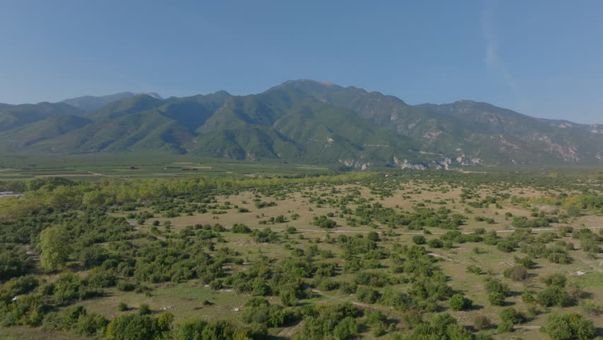 Camera pans over a beautiful mountain range with lush green valleys below. Mount olympus, the highest mountain in Greece, is visible in the distance