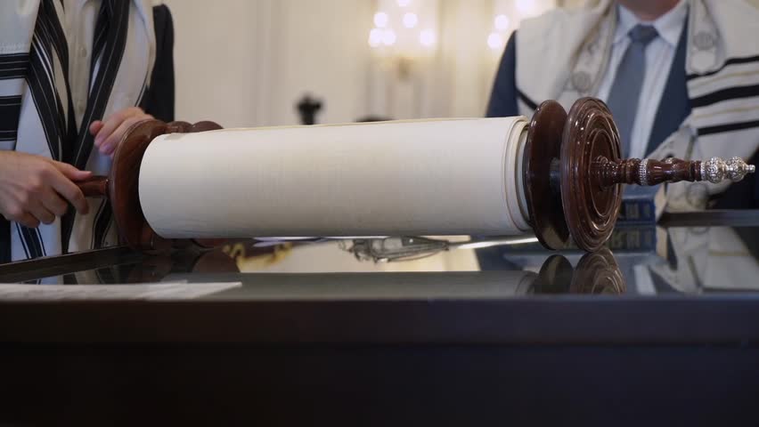 A crafted Torah scroll is showcased during a religious ceremony, highlighting its cultural importance