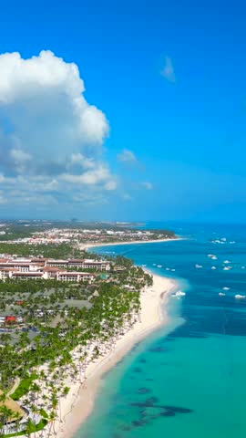 Vertical high aerial view of the Punta Cana coast with many all inclusive hotels. Large white sand beach and turquoise water of the Caribbean sea. Best summer vacations for family and honeymoon